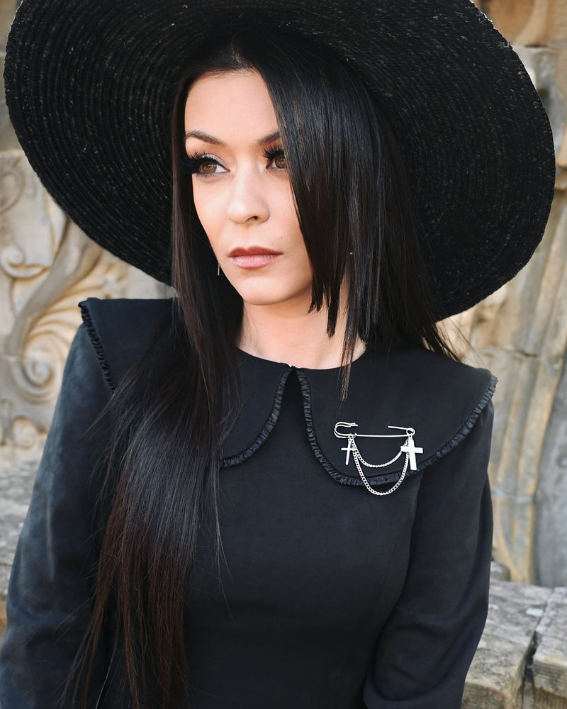Oversized silver-tone safety pin brooch featuring two sleek cross charms connected by draped chains. Measuring 2.6 inches, this edgy gothic accessory adds a bold statement to collars, coats, or bags, blending punk-inspired style with elegant detailing.