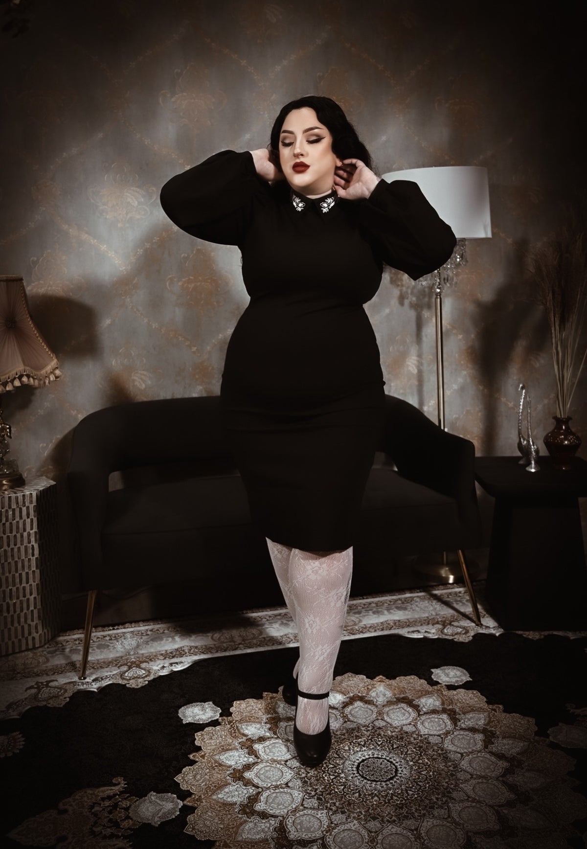 A fitted black dress with long puff sleeves and a high neckline, featuring a jeweled collar detail that adds a touch of elegance. The dress has a sleek, classic silhouette that flatters the figure, perfect for a polished and timeless look.