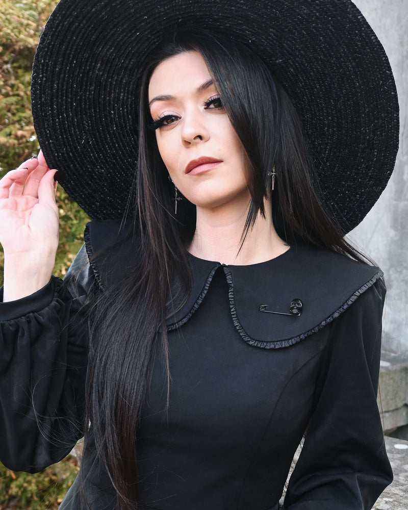 Stylish matte black safety pin brooch with detailed skull accent, 2 inches in length. Ideal for gothic or alternative fashion lovers, this small but striking accessory enhances collars, lapels, or coats with bold individuality.