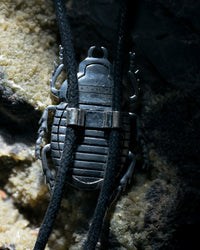 Metallic pendant with textured surface on a dark background