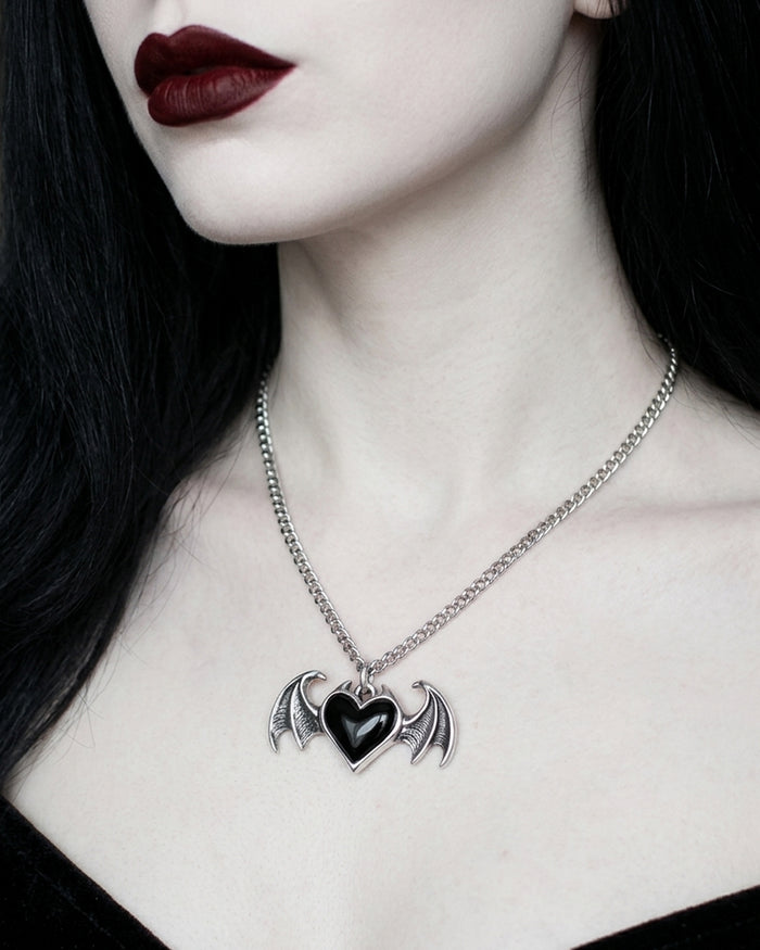 Necklace with a bat-shaped pendant featuring a heart on a plain background