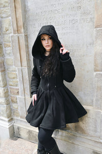 The gothic hoodie dress features a structured yet comfortable silhouette designed for colder weather. Made from thick, high-quality 400 GSM cotton with a soft fleece interior, it has a fitted waist that transitions into a flowing full skater skirt. The dress is finished with a deep hood, large functional pockets, and a gothic cross zipper detail, combining everyday practicality with dark romantic style.