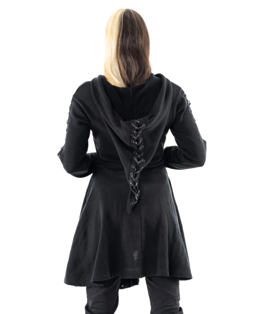 A black longline cardigan with a whimsical pointed hood and intricate corset-inspired detailing throughout. The Fialka Cardigan is crafted from comfortable knit fabric and designed with an oversized elfish hood featuring continuous lace-up grommet accents along the back. Eyelet lacing runs down the outer sleeves and highlights the front hem, creating a cohesive dark romantic look. The front zip closure and matching tie belt allow the silhouette to be worn loose and flowing or cinched closer to the waist.