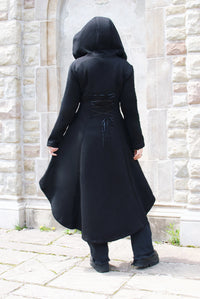 A gothic-inspired black hoodie with a dramatic elongated high-low cut, oversized hood, and corset-style lacing along the back. Made from 100% heavyweight 400 GSM cotton, the thick fabric has a soft feel and warm fleece lining for colder weather. Deep pockets add everyday practicality, while the black front zipper features a distinctive cross-shaped handle that enhances the dark romantic design.