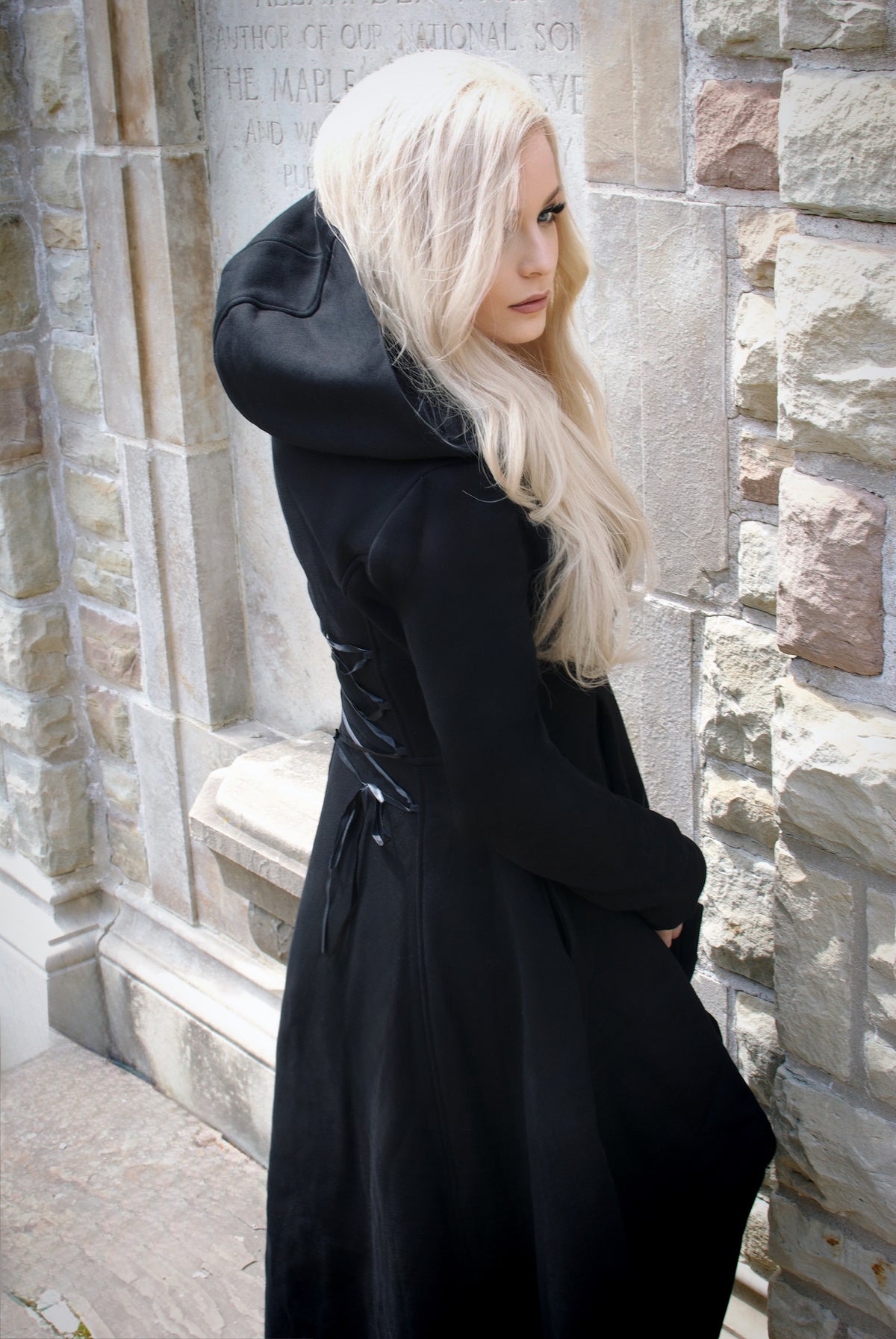The long high-low hoodie features a striking black silhouette with an oversized hood and dramatic corset-style lacing across the back. Crafted from thick, soft 400 GSM cotton with a warm fleece lining, it offers cozy coverage for colder seasons. Deep pockets add functionality, while the black front zipper and gothic cross zipper pull complete the dark romantic aesthetic. A versatile statement layer for alternative wardrobes.