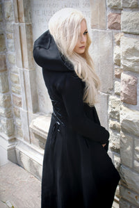 The long high-low hoodie features a striking black silhouette with an oversized hood and dramatic corset-style lacing across the back. Crafted from thick, soft 400 GSM cotton with a warm fleece lining, it offers cozy coverage for colder seasons. Deep pockets add functionality, while the black front zipper and gothic cross zipper pull complete the dark romantic aesthetic. A versatile statement layer for alternative wardrobes.