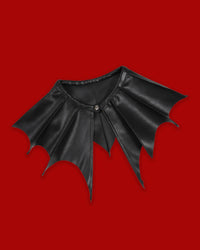 A striking gothic detachable collar with dramatic batwing-shaped panels and sharp pointed lines extending across the shoulders. The Nightwing Collar creates a bold, structured silhouette and can instantly transform simple outfits without requiring a full gothic look. Designed for easy layering over dresses, tops, knitwear, or jackets, it adds theatrical edge to monochrome, dark-academic, festival, and alternative styling.