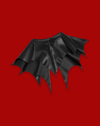 A dramatic black detachable collar featuring sharp, pointed batwing-inspired panels that extend across the shoulders for a distinctive gothic silhouette. The Nightwing Collar is designed as a versatile statement accessory that can be layered over everyday tops, dresses, knitwear, or jackets. Its theatrical shape adds dark-academic elegance to tailored outfits or creates a striking alternative look when styled with mesh, corsetry, and platforms.