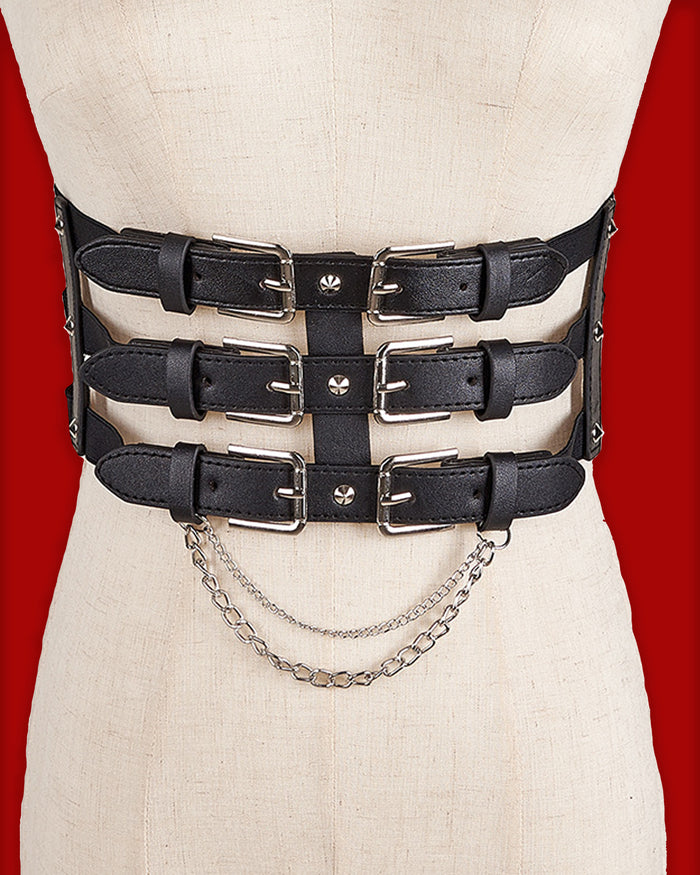 The Nocturne Harness Belt features a triple-tiered front made from structured black synthetic leather, detailed with six silver-toned buckles for a bold industrial look. Available in a classic version or with a detachable layered silver chain, it offers versatile styling options. A wide elastic back band provides a comfortable, cinched fit, while secure snap closures make it easy to layer over dresses, blazers, or oversized shirts.