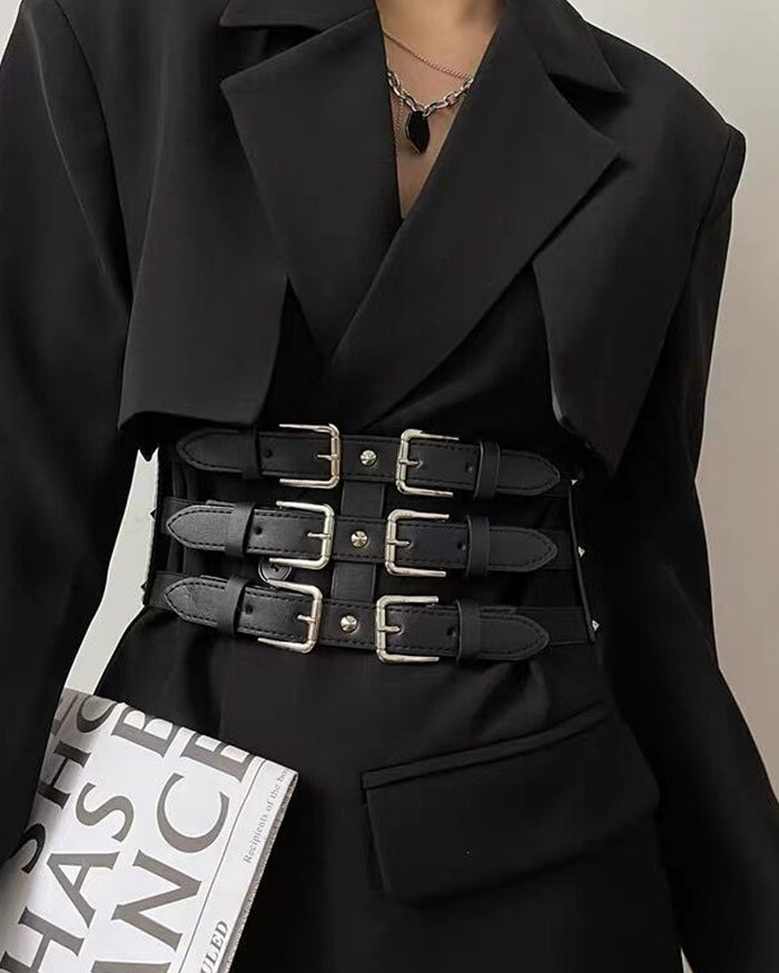 A dramatic black waist harness belt combining structured synthetic leather with six silver-toned buckles across its triple-tiered front. The Nocturne Harness Belt can be styled in a sleek classic version or with a detachable layered silver chain for added detail. Its wide elastic back band comfortably cinches the waist, while snap-button closures allow for easy layering over dresses, blazers, shirts, and other oversized garments.