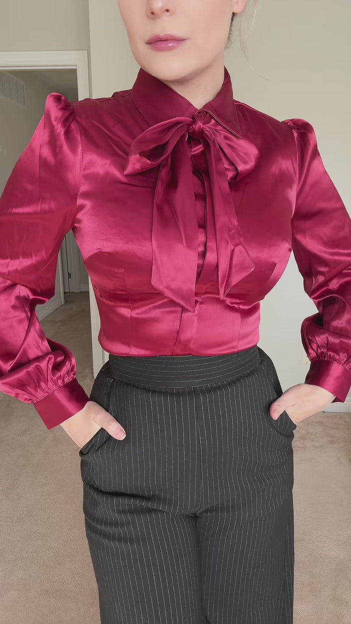 Woman shows a burgundy satin blouse with oversized bow