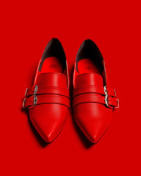 Front view of the Antonella flat shoes in red against a red background.