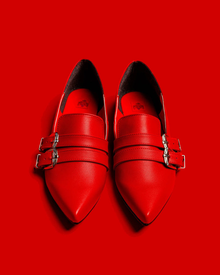 Front view of the Antonella flat shoes in red against a red background.