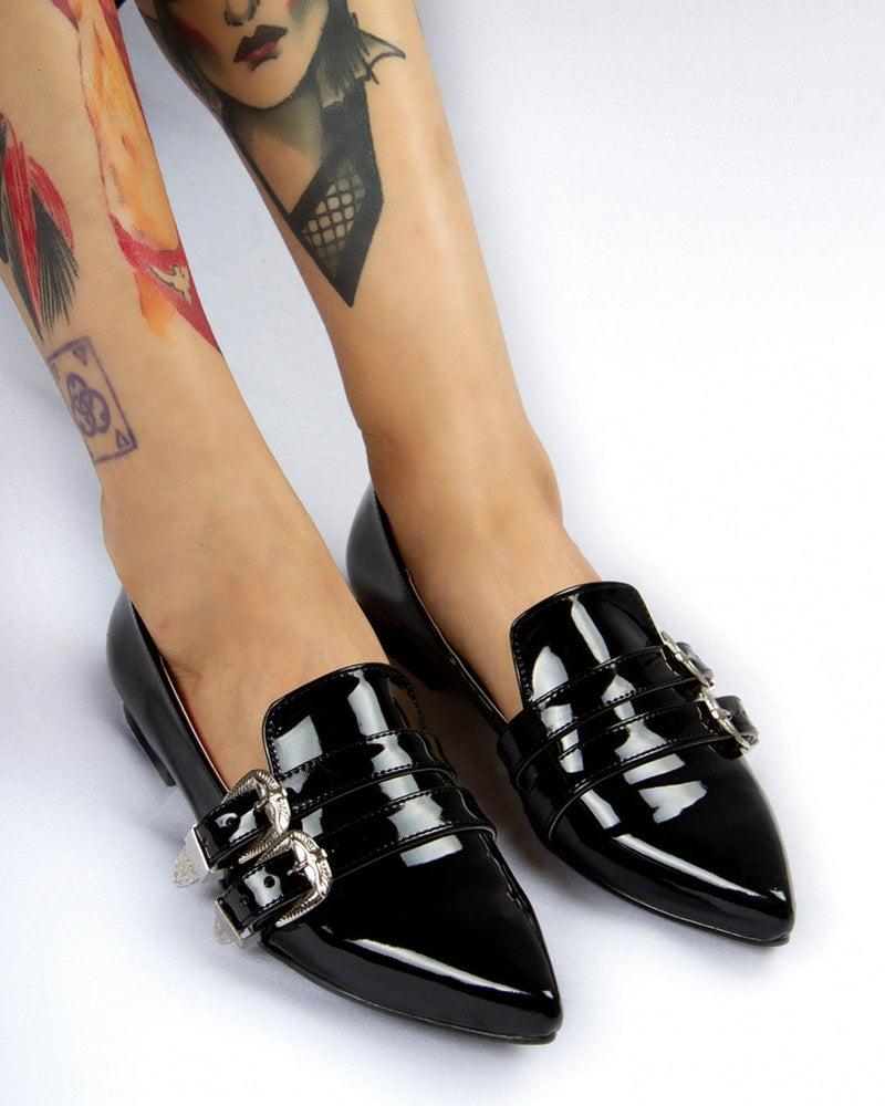 Model feet closeup against a white background while wearing the Antonella flat shoes in patent black.