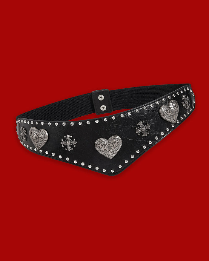 The Wild Heart Belt is a western-inspired statement waist belt featuring intricate silver-toned heart and cross hardware on a textured synthetic leather front. Its distinctive V-shaped design draws the eye inward to create a flattering, slimming effect at the waist. A wide elastic stretch band at the back provides comfortable flexibility, while double snap buttons ensure a secure and easy fit.
