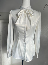 The Angela Blouse in white on a white bust mannequin against a white wall.
