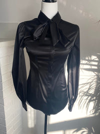 The Angela Blouse in black on a white bust mannequin against a white wall.