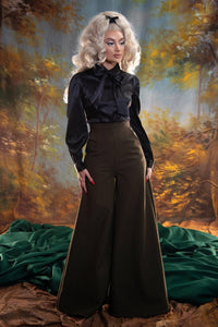 The Angela Blouse in black is a sophisticated poly satin top featuring a cinched, ultra-stretchy waist that flatters every silhouette, paired with elegant flowing bishop sleeves for a dramatic yet balanced look. Complete with a matching bow for added style, this versatile blouse can be worn alone or layered under the Vera Vest for a tailored ensemble. Perfect for formal occasions, office wear, or elevated everyday fashion, it combines classic elegance with modern design.