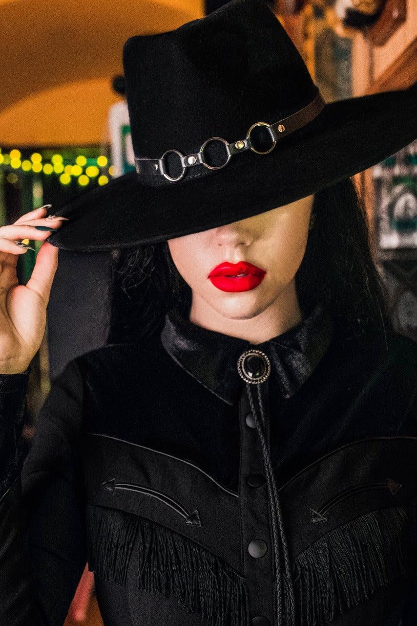 Bondage-inspired vegan leather hat belt featuring three metal o-rings, designed to add edgy, gothic flair to any Katakomb wool hat. Handcrafted and removable, this versatile one-size accessory fits all hats in the collection and enhances alternative, punk, and dark fashion styles.