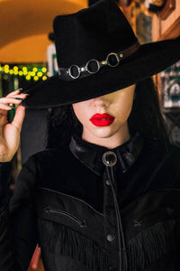 Bondage-inspired vegan leather hat belt featuring three metal o-rings, designed to add edgy, gothic flair to any Katakomb wool hat. Handcrafted and removable, this versatile one-size accessory fits all hats in the collection and enhances alternative, punk, and dark fashion styles.