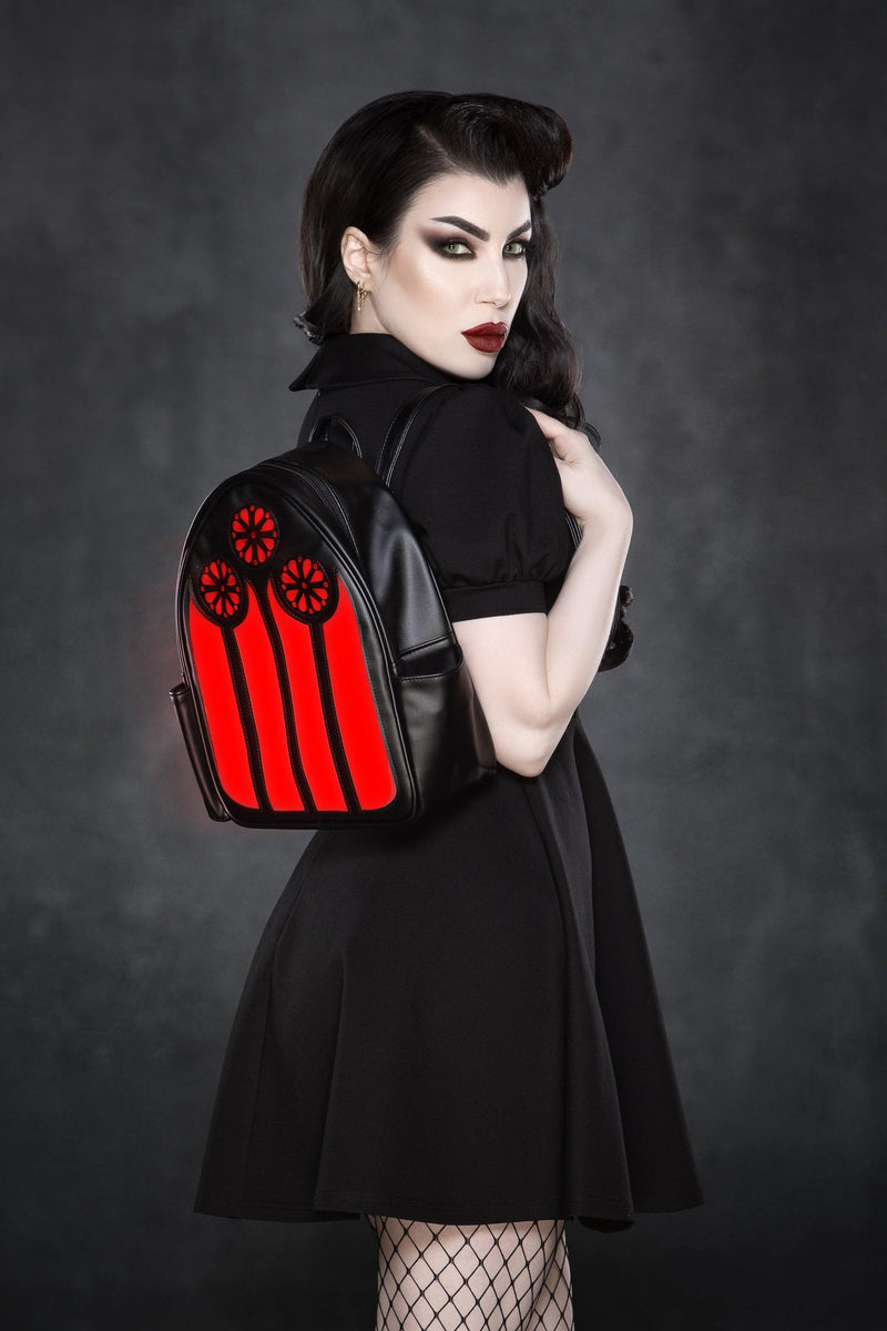 A gothic-inspired vegan leather LED backpack featuring a striking stained glass window design that illuminates in vibrant red, green, and purple tones or switches to a sleek black-and-white mode. Perfect for festivals, school, or everyday adventures, this stylish accessory blends spooky cathedral aesthetics with modern tech flair.