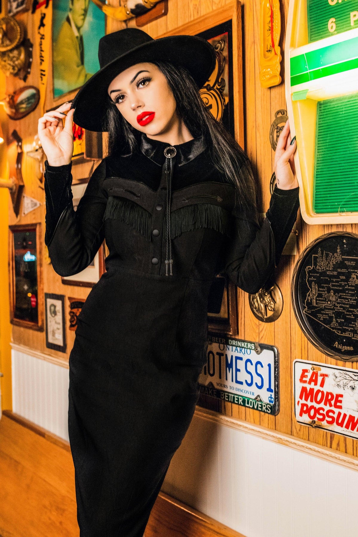 The black Loretta Dress merges vintage Western aesthetics with modern design, featuring a cheeky fringe, elegant arrow detailing along the bust, pleather yoke accents, and rich faux velvet panels, all meticulously handmade from high-quality bengaline fabric to create a statement piece that is as comfortable as it is stylish.