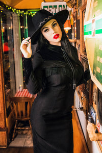 The black Loretta Dress offers a unique combination of Western-inspired charm and contemporary fashion, with a cheeky fringe, arrow detailing along the bust, pleather yoke accents, and faux velvet panels, all handmade from high-quality bengaline fabric for a comfortable, eye-catching, and statement-making dress.