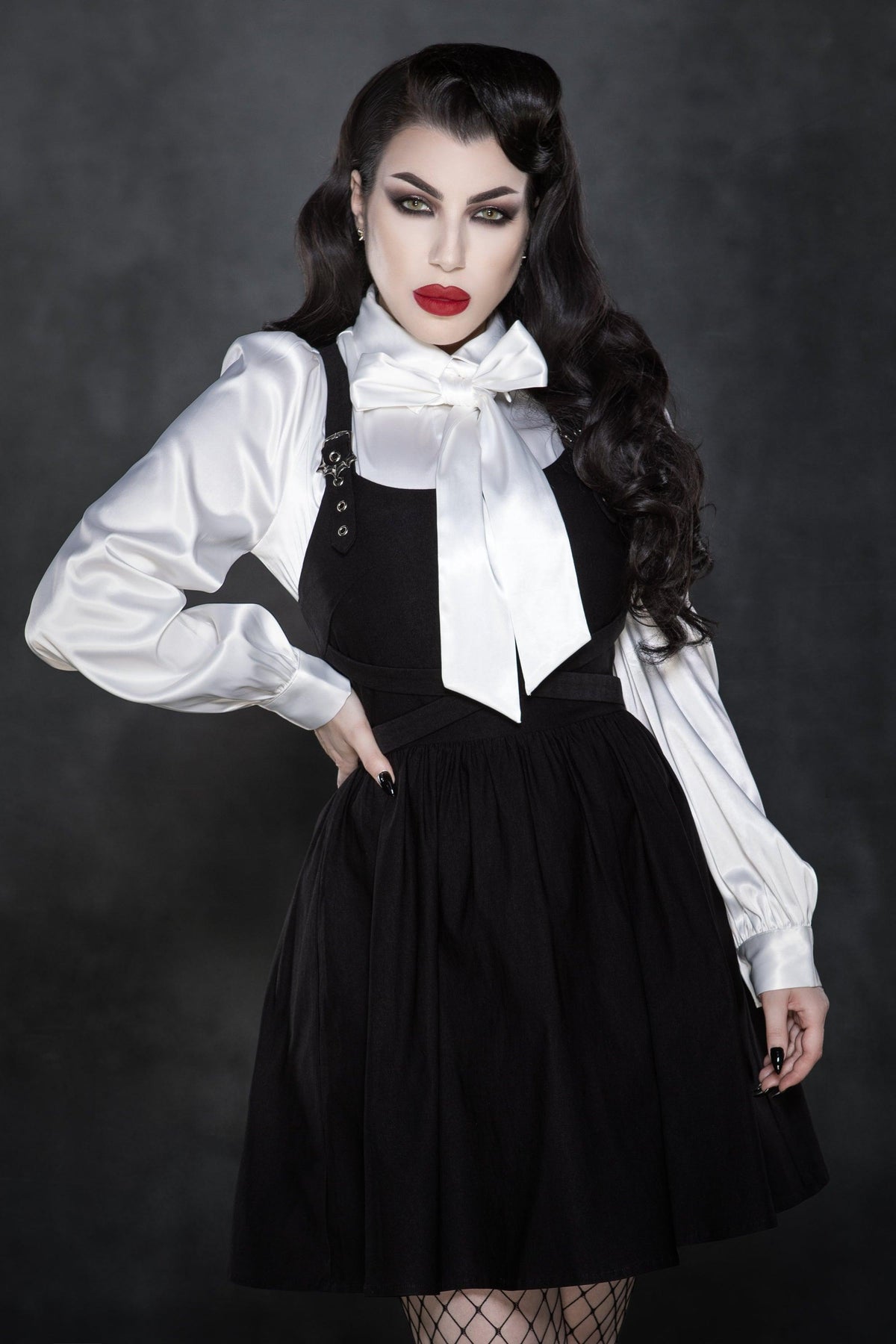 Designed to flatter, this black skater-style dress in soft yet structured Bengaline fabric features a striking cross-strap neckline, a tailored bodice flowing into a full A-line skirt that moves beautifully, fine embroidered detailing across the chest, and unique webbed buckle hardware that gives the piece a subtle industrial-chic twist.