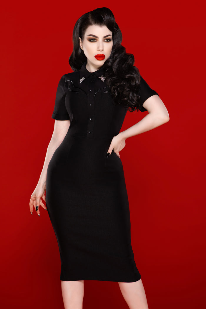 Crafted from premium stretch Bengaline, the Wanda Pencil Dress delivers both comfort and structure, hugging the figure to create an effortlessly chic silhouette. The elegant black design features faux front snaps, an easy-access back zipper, and stylish pleather piping that adds a luxurious touch. Complete with two removable silver collar clips for a playful Western twist, this dress is a versatile must-have for refined yet edgy fashion lovers.